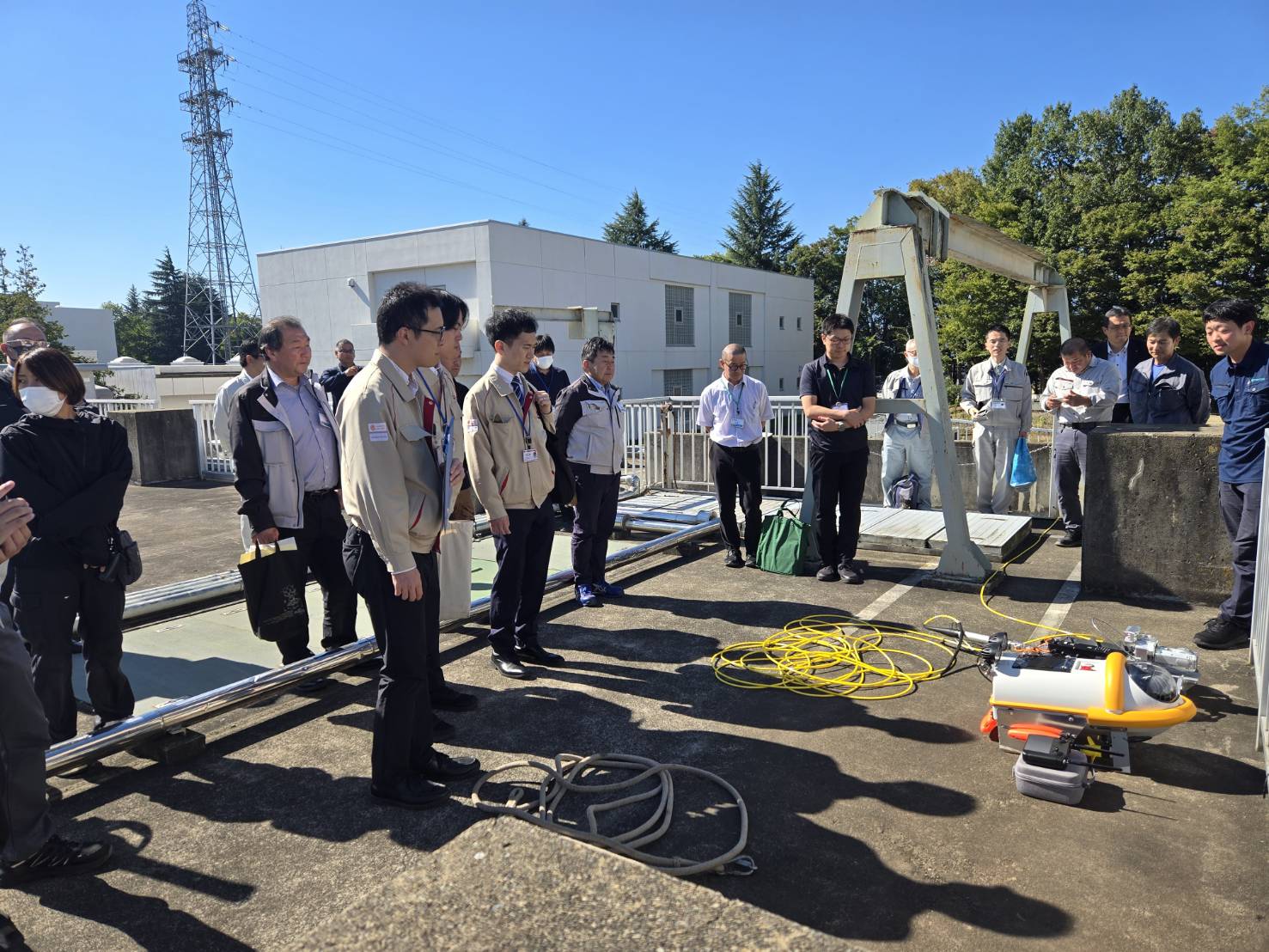 屋外で調査機器の説明と実演を見学する勉強会の参加者